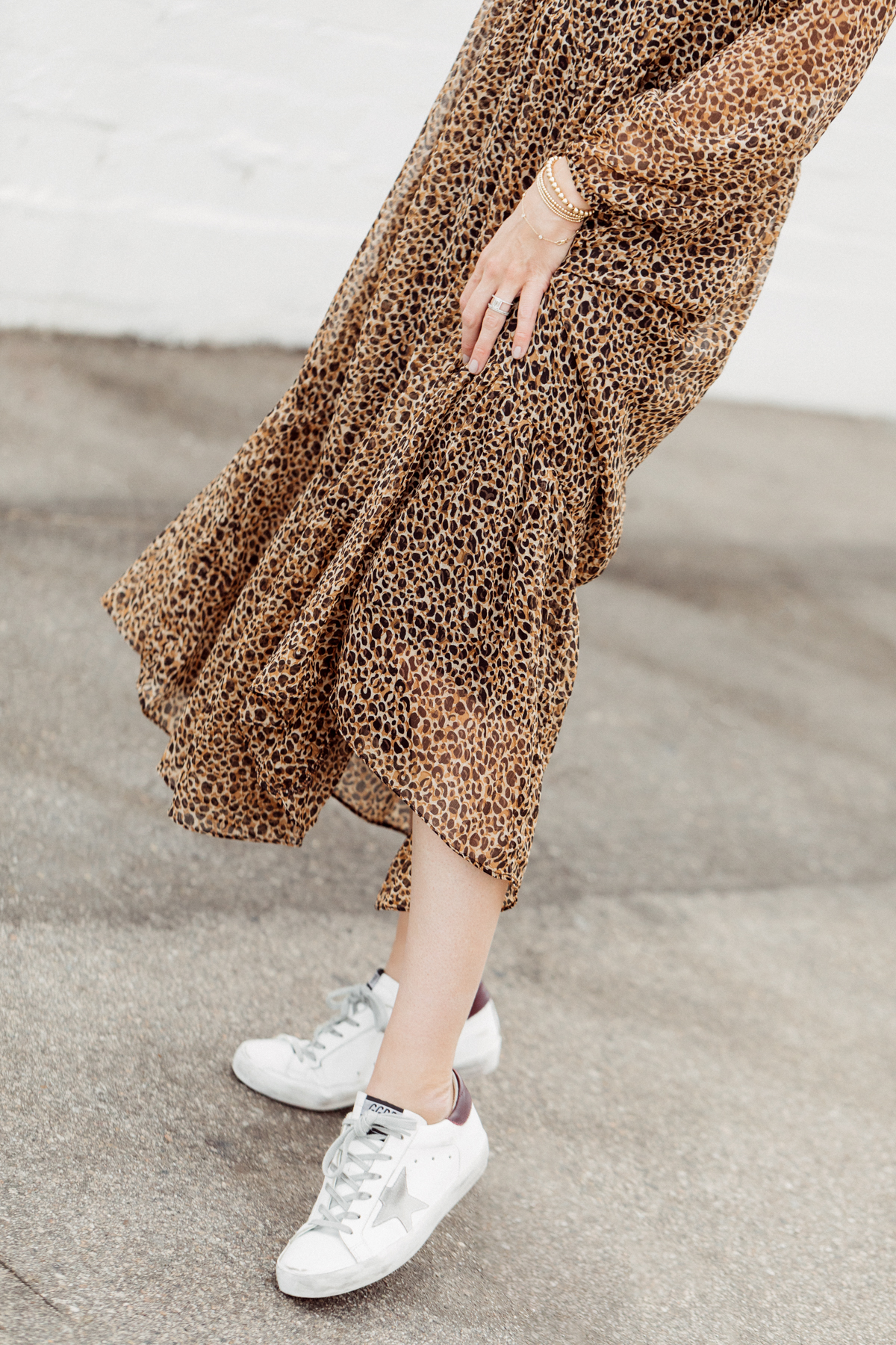 Kimberly Lapides of eatsleepwear wearing a long leopard maxi dress from h&m and golden goose sneakers with ray-ban sunglasses.