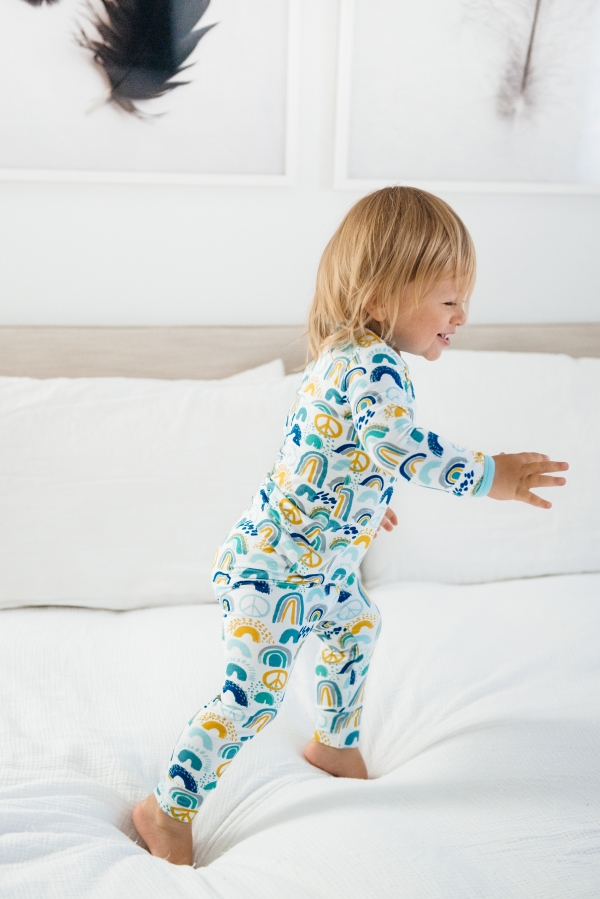 Toddler jumping on bed in Clover Baby & Kids pajamas celebrating Rainbow Baby, IVF, and Infertility