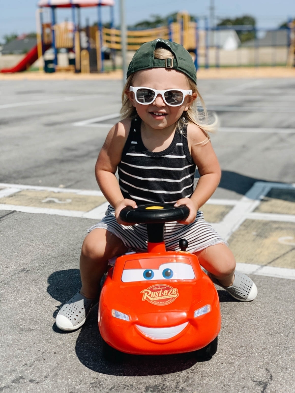 Otis riding in his lightning mcqueen ride-on toy for trolls theme birthday