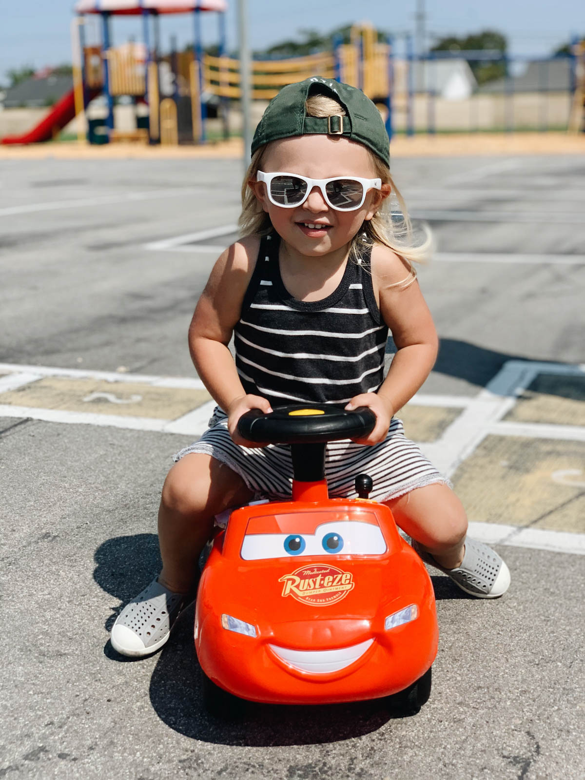 Otis riding in his lightning mcqueen ride-on toy for trolls theme birthday