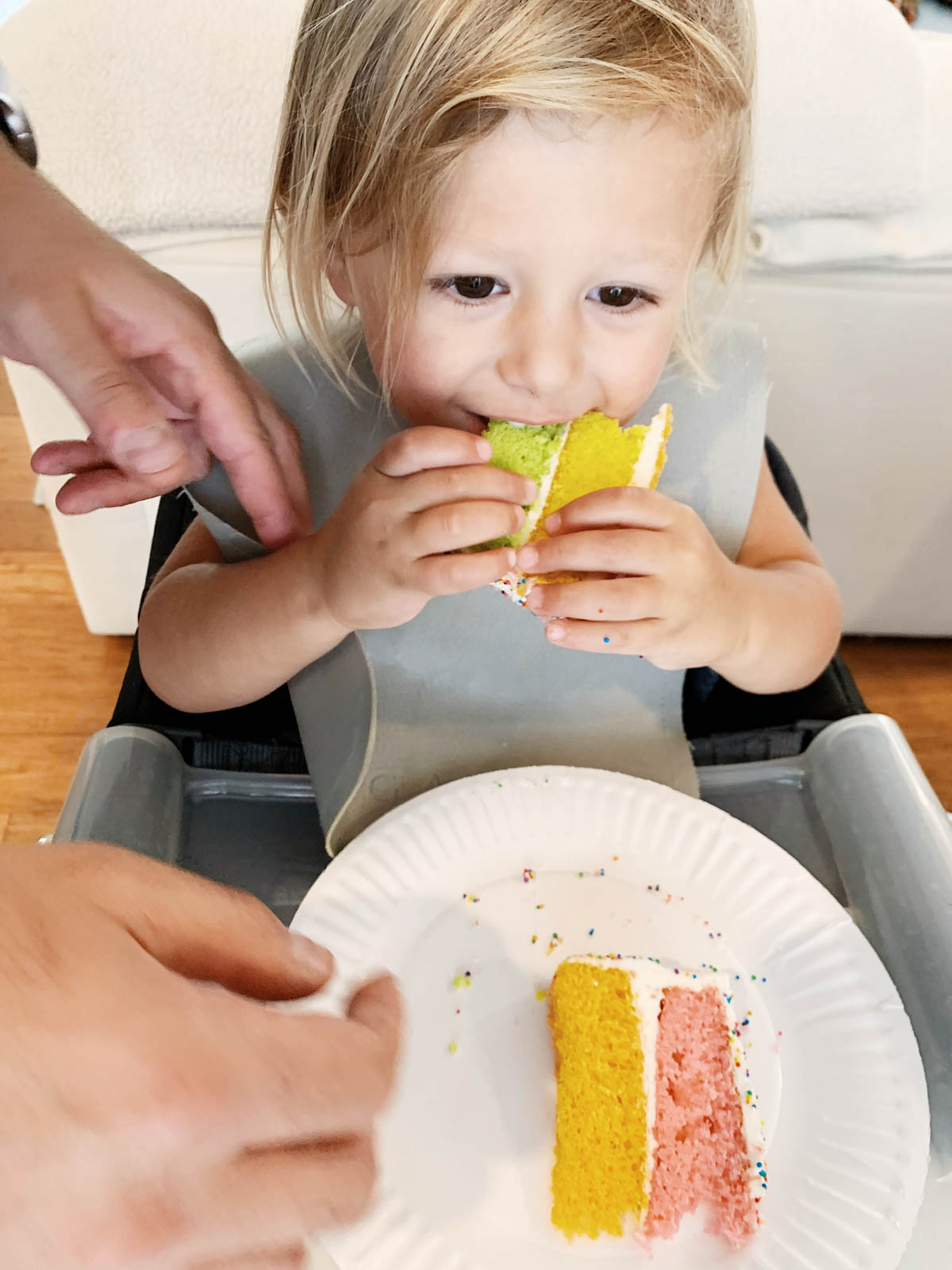 Otis eating rainbow sprinkle cake with Trolls figurines for Trolls theme birthday