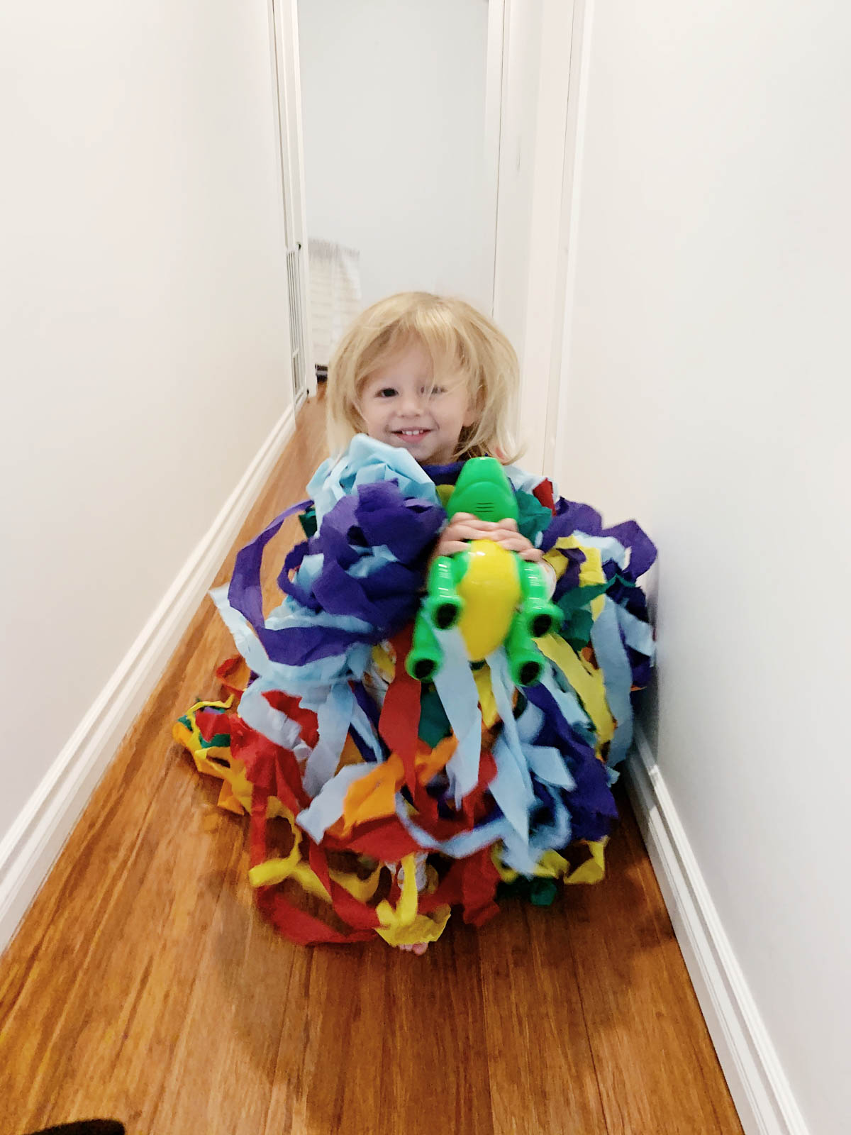 Toddler running with streamers from Trolls theme birthday