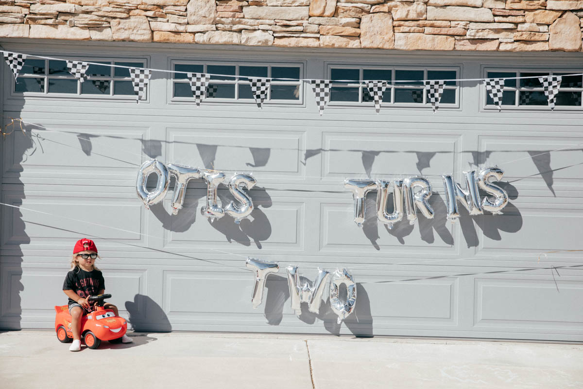 Balloons and Toddler using Ride on Lightning McQueen Car Toy at Disney Pixar Cars themed birthday