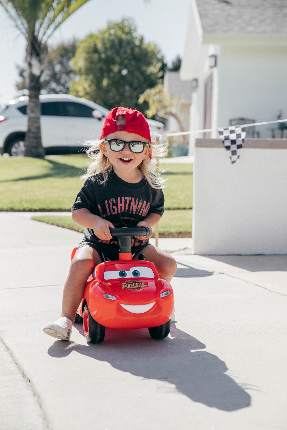 Toddler with ride on Lightning McQueen Car Toy at Disney Pixar Cars themed birthday