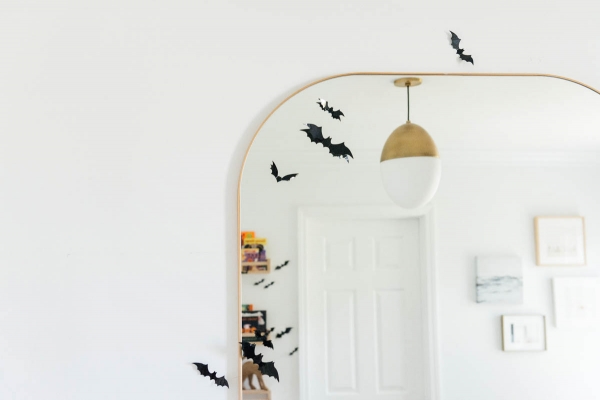 Best Halloween Books for Toddlers styled on wooden shelves with bat wall decals in nursery with modern mirror
