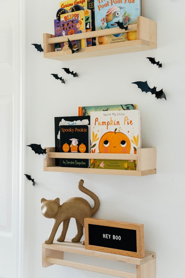 Best Halloween Books for Toddlers styled on wooden shelves with bat wall decals