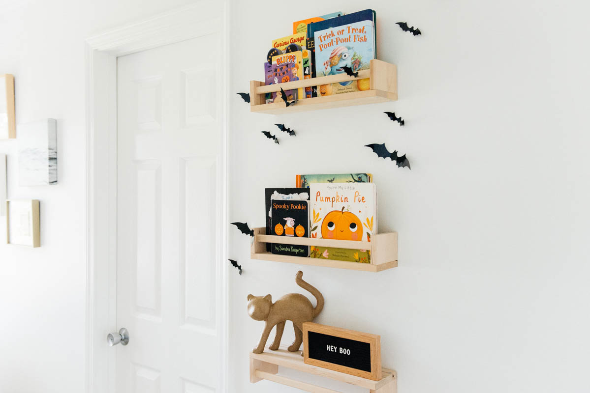 Best Halloween Books for Toddlers styled on wooden shelves with bat wall decals in nursery