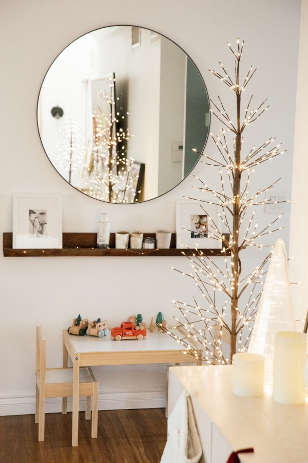 Indoor Holiday decor of twinkle lights tree, twinkle lights, clear glass Christmas tree cloche, kids table and kids Christmas truck toys