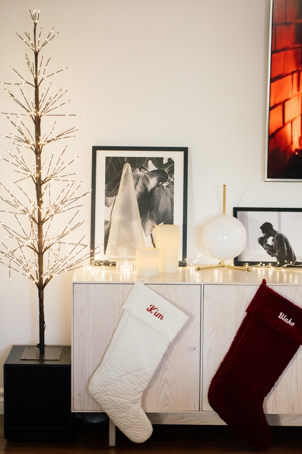 Indoor Holiday decor of twinkle lights tree, twinkle lights, clear glass Christmas tree cloche, and custom embroidered stockings 